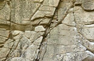 Light coarse natural rock stone background. Mining cliff rough front surface. Big limestone stack backdrop. Heavy grunge damaged granite block texture photo