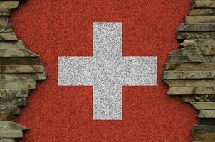 Switzerland flag depicted in paint colors on old stone wall closeup. Textured banner on rock wall background photo