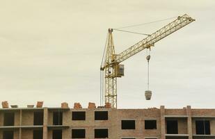 View of a large construction site with buildings under construction and multi-storey residential homes. Tower cranes in action on blue sky background. Housing renovation concept photo