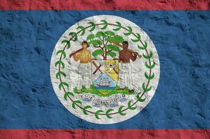 Belize flag depicted in bright paint colors on old relief plastering wall. Textured banner on rough background photo