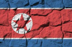 North Korea flag depicted in paint colors on old stone wall closeup. Textured banner on rock wall background photo