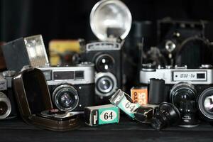 KHARKOV, UKRAINE - APRIL 27, 2021 Film photo cameras and another old retro photo equipment on black wooden table in photographer darkroom. Photographic gear from soviet union