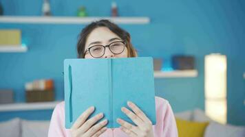 Fun young woman looking behind book. video