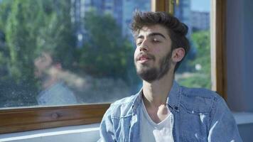 Happy man looks out the window and takes a deep breath. video