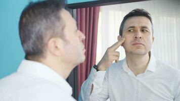 The man looking at the wrinkles on his face in the mirror. video