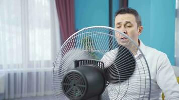 abrumado por el calor, el hombre vueltas en el ventilador y relaja video