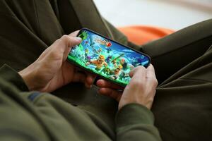 Clash of Clans mobile iOS game on iPhone 15 smartphone screen in male hands during mobile gameplay photo