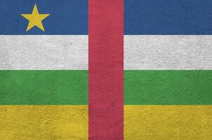 Central African Republic flag depicted in bright paint colors on old relief plastering wall. Textured banner on rough background photo