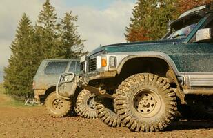 Automobile in a countryside landscape with a mud road. Off-road 4x4 suv automobile with ditry body after drive in muddy road photo