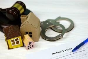 Notice to quit or eviction notice blank document paper ready to fill with judgement gavel, handcuffs and small toy houses on table photo