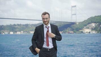 Businessman fixing tie by the sea. video