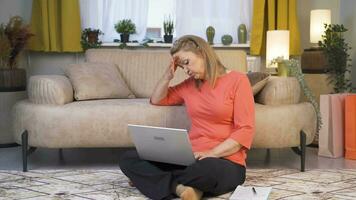 Woman working on laptop has a headache. video