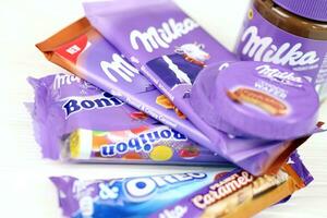 kharkov, ucrania - 2 de julio de 2021 productos de chocolate milka con diseño de envoltura de color lila clásico en mesa blanca foto