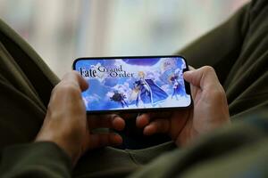 Fate Grand Order mobile iOS game on iPhone 15 smartphone screen in male hands during mobile gameplay photo