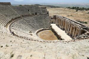 ANTALYA, TURKEY - MAY 15, 2021 Ruins of amphitheatre in ancient city Hierapolis near Pamukkale, Turkey at sunny day. Parts of old historical buildings with big blocks photo