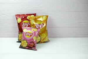 KHARKOV, UKRAINE - JANUARY 3, 2021 Various flavoured of lay's potato chips on wooden background. Lay's has been owned by PepsiCo through Frito-Lay in 1965 photo