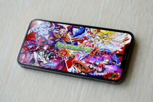 Monster Strike mobile iOS game on iPhone 15 smartphone screen on wooden table during mobile gameplay photo