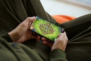 Clash of Clans mobile iOS game on iPhone 15 smartphone screen in male hands during mobile gameplay photo