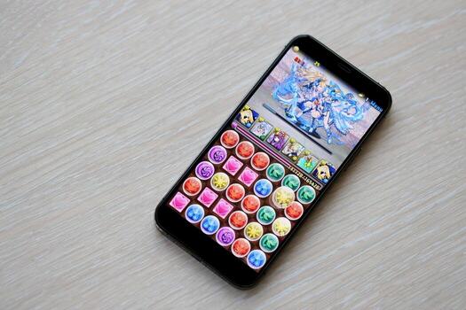 Puzzle and dragons mobile iOS game on iPhone 15 smartphone screen on wooden table during mobile gameplay photo