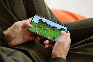 Minecraft mobile iOS game on iPhone 15 smartphone screen in male hands during mobile gameplay photo