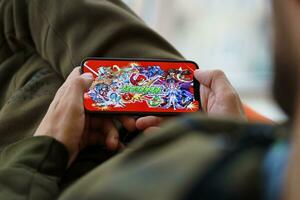 Monster Strike mobile iOS game on iPhone 15 smartphone screen in male hands during mobile gameplay photo