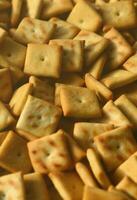 Background texture of small edible squares baked from dough and sprinkled with salt. A lot of salt cracker photo