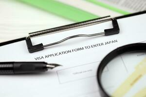 Visa application to enter Japan on A4 tablet lies on office table with pen and magnifying glass photo