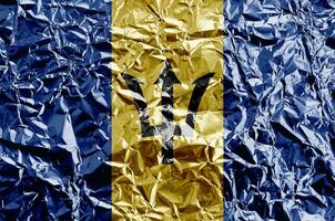 Barbados flag depicted in paint colors on shiny crumpled aluminium foil closeup. Textured banner on rough background photo