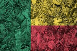 Benin flag depicted on many leafs of monstera palm trees. Trendy fashionable backdrop photo