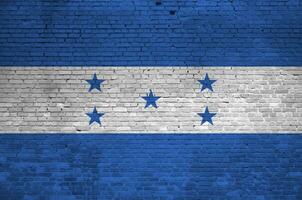 Honduras flag depicted in paint colors on old brick wall. Textured banner on big brick wall masonry background photo