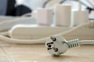 Overloaded power boards. Power strips with different electrical plugs on white floor photo