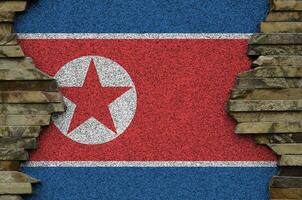 North Korea flag depicted in paint colors on old stone wall closeup. Textured banner on rock wall background photo