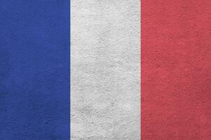 France flag depicted in bright paint colors on old relief plastering wall. Textured banner on rough background photo