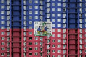 Haiti flag depicted in paint colors on multi-storey residental building under construction. Textured banner on brick wall background photo