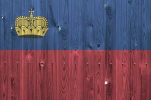 Liechtenstein bandera representado en brillante pintar colores en antiguo de madera pared. texturizado bandera en áspero antecedentes foto