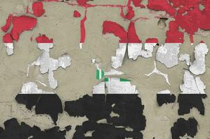 Iraq flag depicted in paint colors on old obsolete messy concrete wall closeup. Textured banner on rough background photo