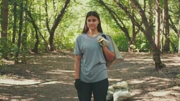 portrait de une bénévole femme qui nettoie le forêt de débris.terre jour, enregistrer planète, enregistrer le monde, l'amour la nature. video