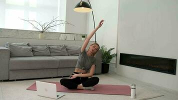 Woman doing physical exercise at home sitting on the floor using online training. video