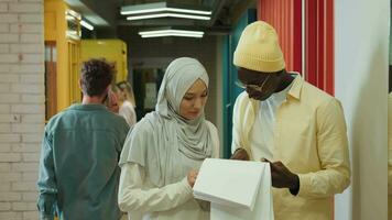 un musulmán negocio mujer y un africano americano empresario son que se discute un proyecto mientras en pie en el corredor.diferente razas diversas gente creativa equipo,negocio socios video