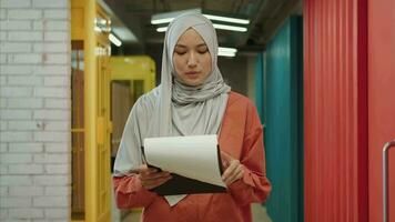 A creative stylish Muslim business woman walks down the corridor with a folder of documents in her hands.Different Races,Diverse People,Creative Team,Business Partners video