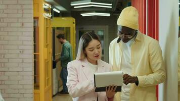 An Asian business woman and an African American businessman are discussing a project while standing in the corridor.Different Races,Diverse People,Creative Team,Business Partners video