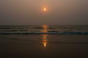 foam of sea or ocean waves against the backdrop of the setting sun photo