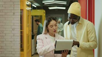 An Asian business woman and an African American businessman are discussing a project while standing in the corridor.Different Races,Diverse People,Creative Team,Business Partners video