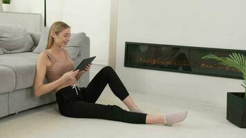 uma mulher usa uma tábua enquanto sentado em a chão perto a sofá e lareira às lar. video