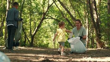 A group of volunteers with a child clean up garbage in the forest.Earth Day, Save Planet, Save the world, Love Nature. video
