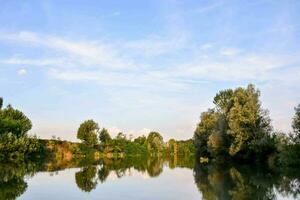 un río con arboles y cielo reflejado en eso foto