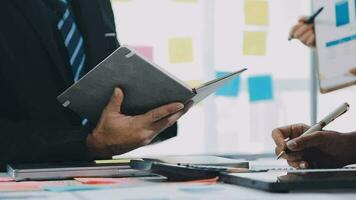 Two creative business people meeting and planning use post it notes sticky note on desk to share idea, Analysis data chart and graph with teamwork strategy brainstorming in office. video