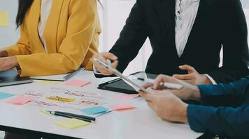 Two creative business people meeting and planning use post it notes sticky note on desk to share idea, Analysis data chart and graph with teamwork strategy brainstorming in office. video