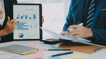 två kreativ företag människor möte och planera använda sig av posta den anteckningar klibbig notera på skrivbord till dela med sig aning, analys data Diagram och Graf med lagarbete strategi brainstorming i kontor. video