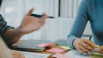 Two creative business people meeting and planning use post it notes sticky note on desk to share idea, Analysis data chart and graph with teamwork strategy brainstorming in office. video